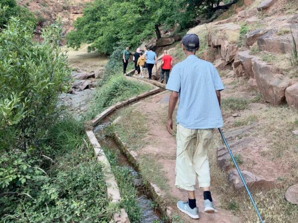 Groupe de randonneurs marchant sur un sentier de montagne entouré de végétation lors de la randonnée aux Gorges de l'Oukaïmeden.